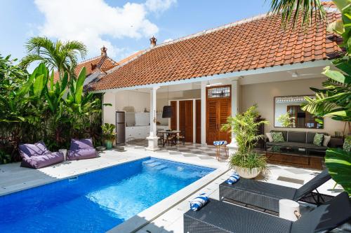a villa with a swimming pool in front of a house at Villa Alliv in Seminyak