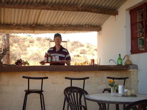 un hombre parado detrás de una barra con una mesa en Capricorn Restcamp, en Rietoog