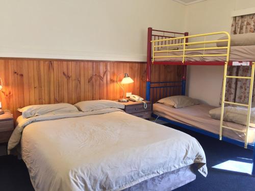 a bedroom with two bunk beds and a desk with a lamp at Lithgow Valley Motel in Lithgow