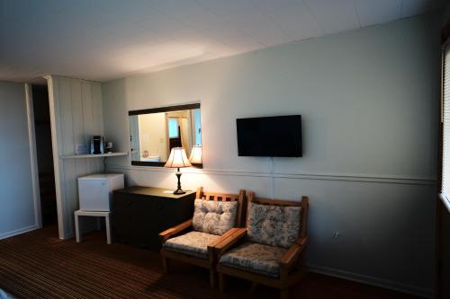 a room with a chair and a desk and a television at Auberge La Coudriere (Cool Hotel) in L'Isle-aux-Coudres