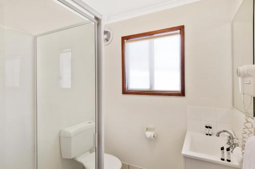 a white bathroom with a toilet and a window at Discovery Parks - Coogee Beach in Coogee
