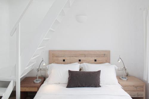 a bedroom with a white bed with a wooden headboard at Ikastikies Suites in Firostefani