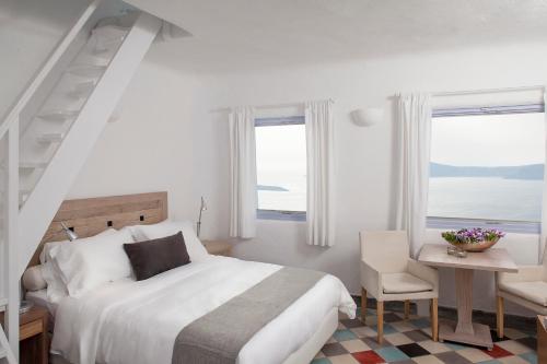 - une chambre avec un lit, une table et des fenêtres dans l'établissement Ikastikies Suites, à Firostefani