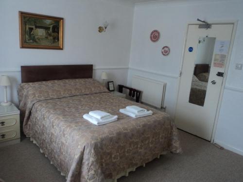 a bedroom with a bed with two towels on it at Arundel Park Hotel in Arundel