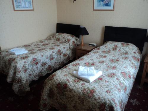 two beds in a hotel room with towels on them at Arundel Park Hotel in Arundel