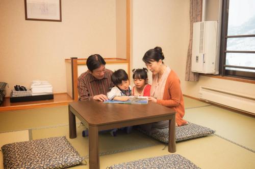 a family sitting at a table reading a book at Hotel Angel Grandia Echigo Nakazato in Yuzawa