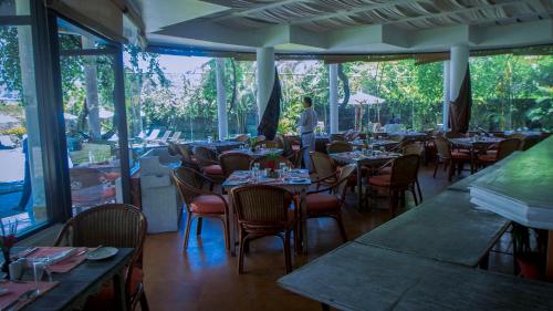a dining room with tables and chairs and windows at Shangri-La Village Resort, Pokhara in Pokhara