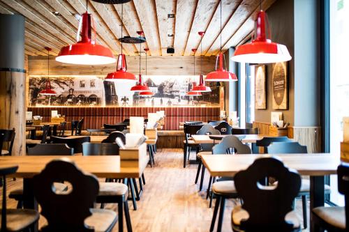 a restaurant with wooden tables and chairs and red lights at RiKu HOTEL Ulm in Ulm
