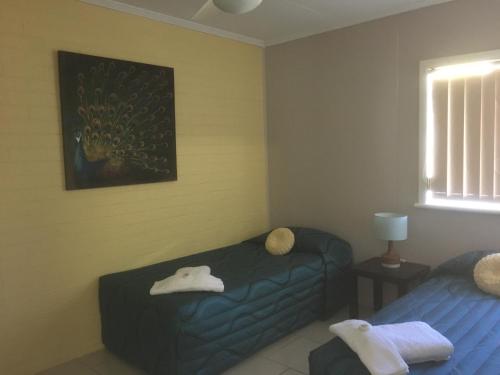 a bedroom with two beds and a painting on the wall at Beachlander Self-Contained Holiday Apartments in Coffs Harbour
