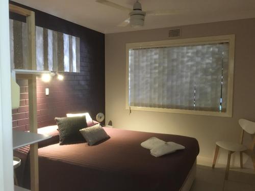 a bedroom with a large bed with a window at Beachlander Self-Contained Holiday Apartments in Coffs Harbour