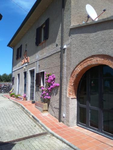 a building with an archway next to a street at SUARA Affitti - bike in Bibbona