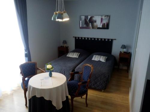 a bedroom with a bed and a table with chairs at Hostellerie le Clos du Cher in Noyers-sur-Cher
