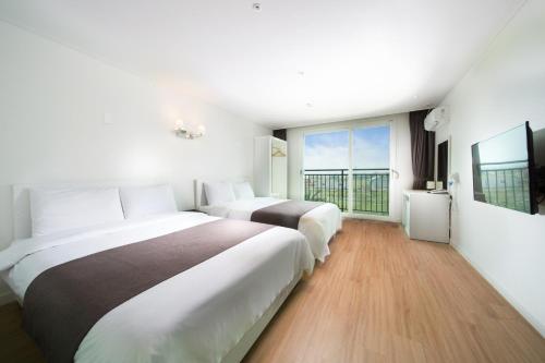 a hotel room with two beds and a large window at Amoureux Resort in Jeju