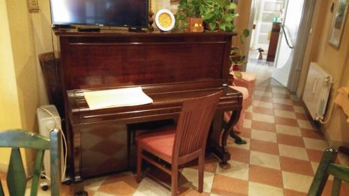 a piano in a room with a chair and a television at Hotel Mance in Brod na Kupi