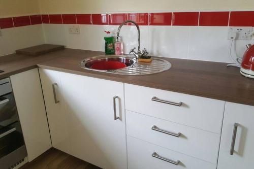 a kitchen with white cabinets and a sink at Stone Eater in Marsden
