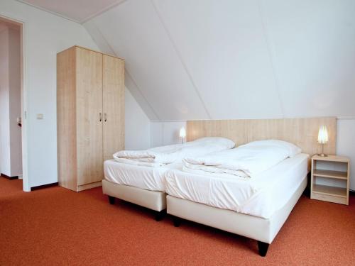 een slaapkamer met 2 witte bedden en een houten hoofdeinde bij Maaspark Boschmolenplas - Tuinblik in Heel