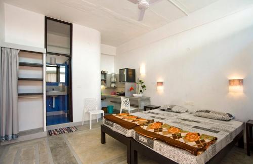 a bedroom with a large bed and a kitchen at Auromode Apartments Auroville in Auroville