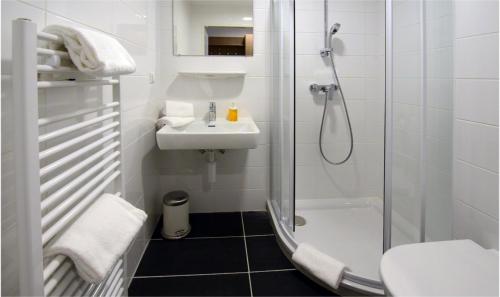 a white bathroom with a sink and a shower at AIS Center in Wolfsberg