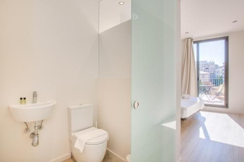 bagno bianco con servizi igienici e lavandino di Flateli - Exclusivo Plaça Catalunya 4-1 a Girona