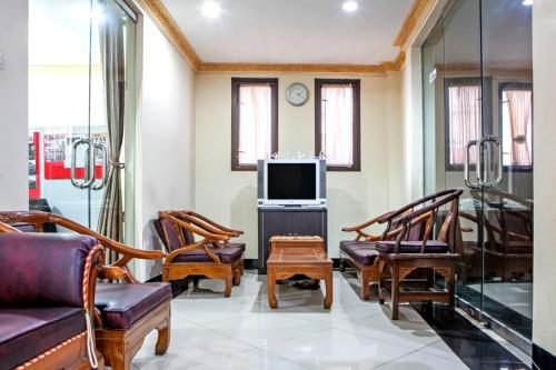 a living room with a couch and chairs and a tv at RedDoorz Plus near Isola UPI in Bandung