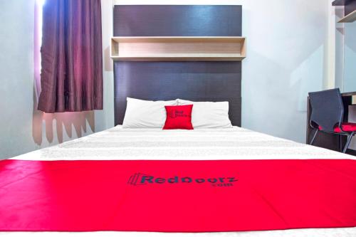 a bed with a red blanket on top of it at RedDoorz Plus near Isola UPI in Bandung
