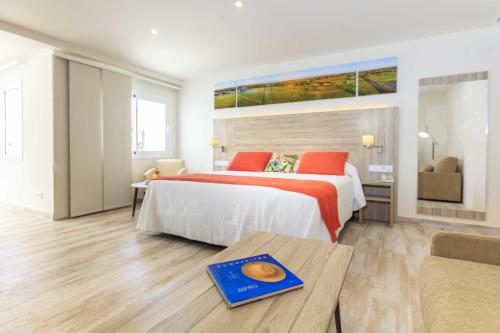 a hotel room with a bed and a table at Hotel Levante in Es Pujols