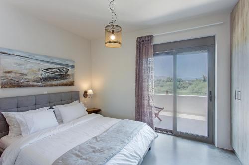 a bedroom with a bed and a sliding glass door at Evais Boutique Houses & Luxury Suites in Karistos