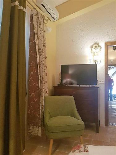 a living room with a green chair and a television at Residenza Villa Spagnola in Parghelia