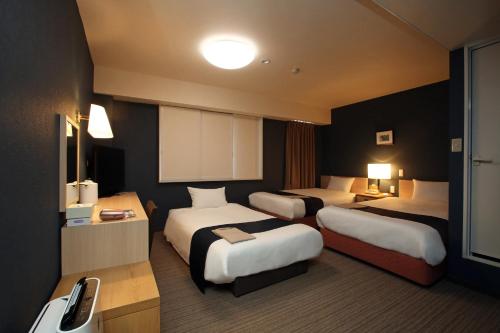 a hotel room with two beds and a bathroom at Country Hotel Takayama in Takayama
