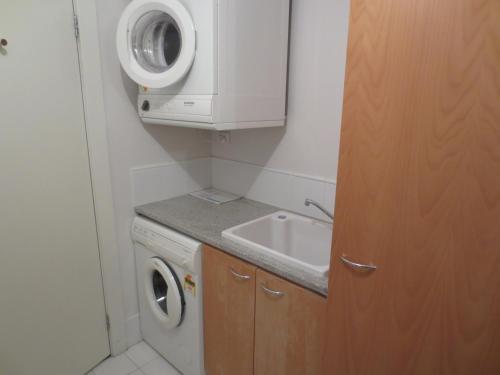 a small bathroom with a washing machine and a sink at Lights Landing Apartments in Adelaide