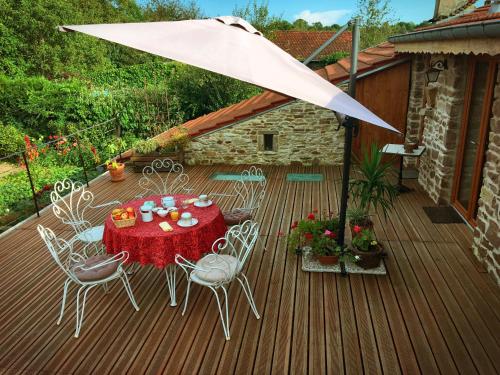 une terrasse en bois avec une table, des chaises et un parasol dans l'établissement Les Chambres d'hotes de Laurette, à Bertrambois