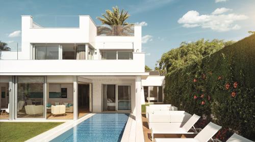 a white house with a swimming pool and white furniture at Puente Romano Marbella in Marbella