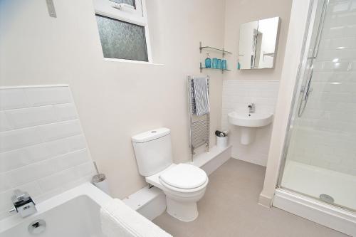 a white bathroom with a toilet and a sink at FREE Parking, Stylish and Spacious Bungalow in Bath