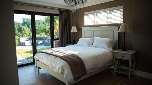a bedroom with a bed and a large window at Knysna Forest View in Knysna