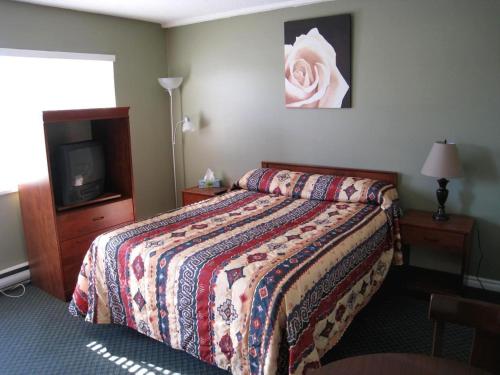 a hotel room with a bed and a tv at Beach Grove Motel in Tsawwassen