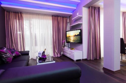 a purple living room with a couch and a tv at Apartmani Pašalić in Tučepi