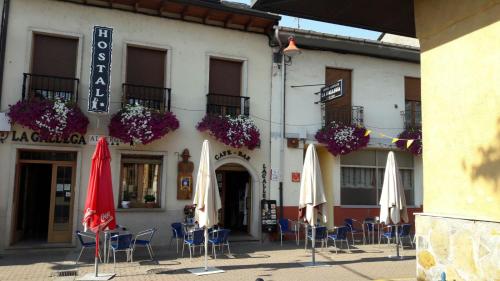 a building with chairs and umbrellas in front of it at La Gallega in Cacabelos