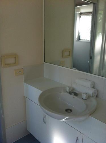 a white bathroom with a sink and a mirror at Bayview Harbourview Apartments in Mooloolaba