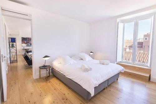 a white bedroom with a large bed and a large window at LovelyStay - Luxury Oasis in Bairro Alto in Lisbon