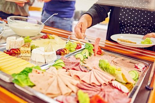 een vrouw bereidt eten in een buffet bij DJH Jugendherberge Biggesee in Olpe