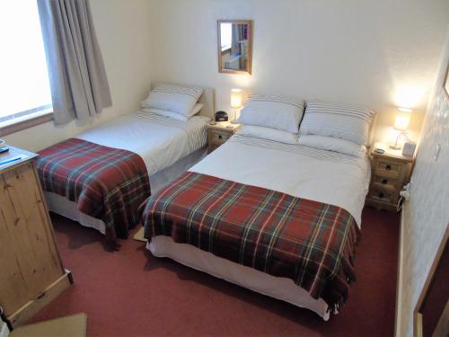 a room with two beds and two lamps and a window at Jomarnic B&B in Lossiemouth