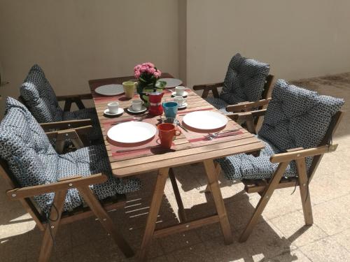 un tavolo e sedie in legno con piatti e fiori di Brezzolina Apartment with parking a Bitonto