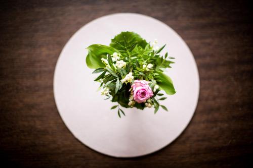 a white plate with a pink flower on a table at Hotel Garni Römerhof in Innsbruck