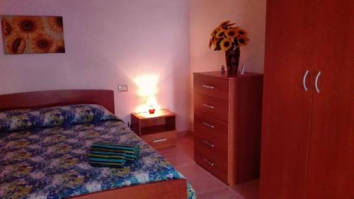 a bedroom with a bed and a dresser with a lamp at Il Girasole Alloggio in Fluminimaggiore