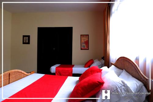 a bedroom with two beds with red and white sheets at Hotel La Herreria Colonial in Popayan