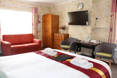 a bedroom with a bed and a desk and a television at The Homestar in Skegness