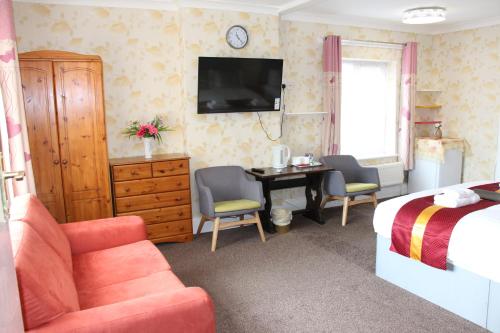 a hotel room with a bed and a desk with a television at The Homestar in Skegness