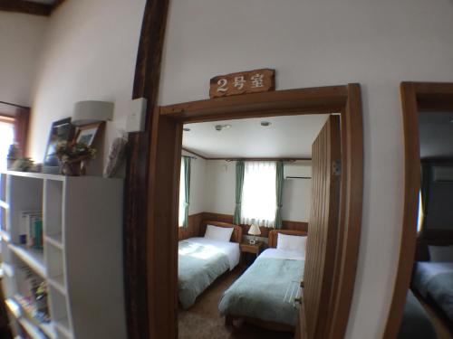 a mirror in a room with two beds and a bedroom at Pension Jokura in Hakodate