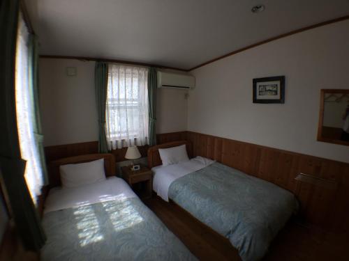 a small room with two beds and a window at Pension Jokura in Hakodate