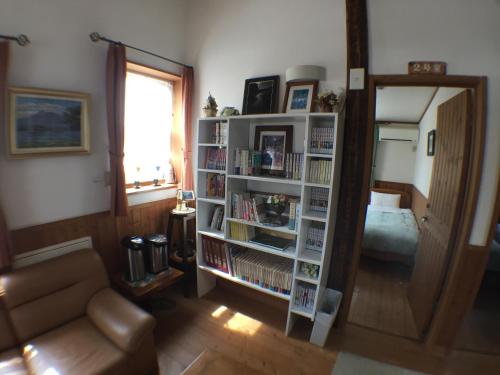 a living room with a book shelf filled with books at Pension Jokura in Hakodate